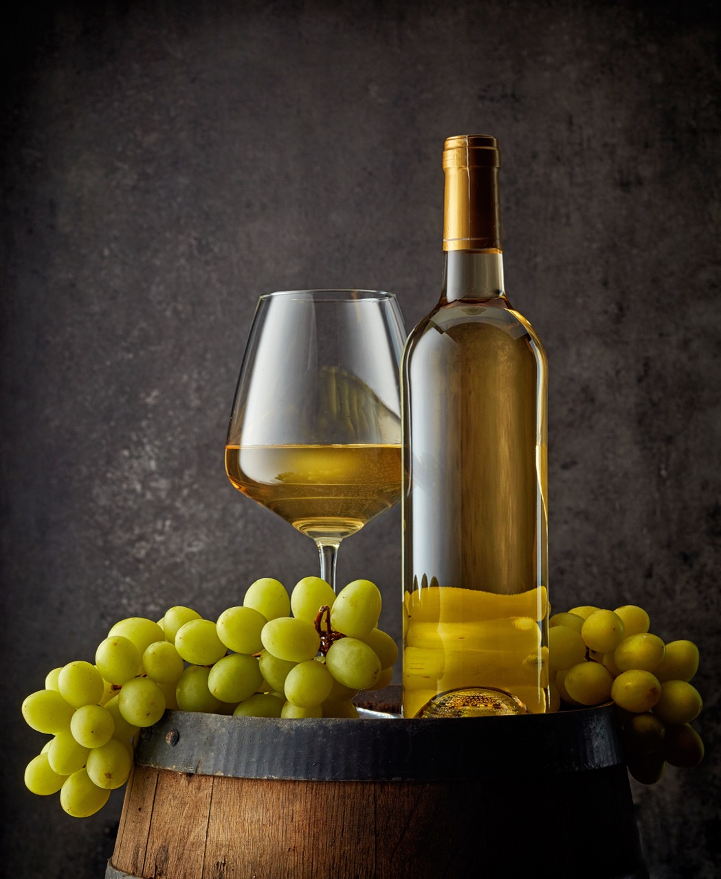 glass and bottle of wine on old wooden barrel