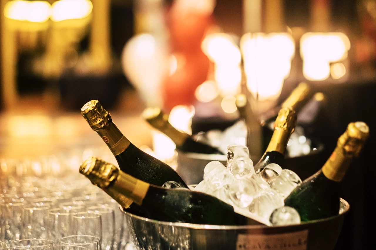 Night event party celebration concept with fluts glasses and wine champagne bottles ready to be drinked from people - bokeh defoused light background