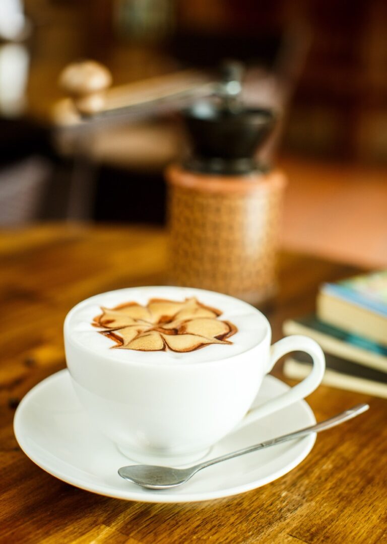Cappuccino with fresh coffee beans, water and books on a brown background