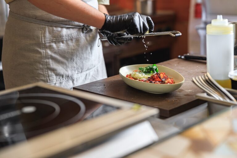 Professional chef grates Parmesan cheese on ready dish in restaurant kitchen. High quality photo