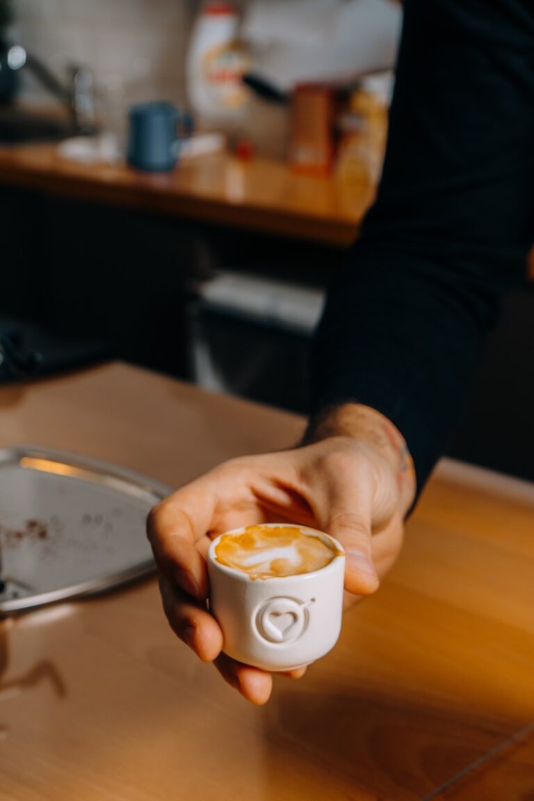 A shallow focus of a man holding a cup of coffee in the kitchen