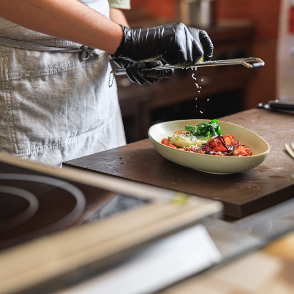 Professional chef grates Parmesan cheese on ready dish in restaurant kitchen. High quality photo